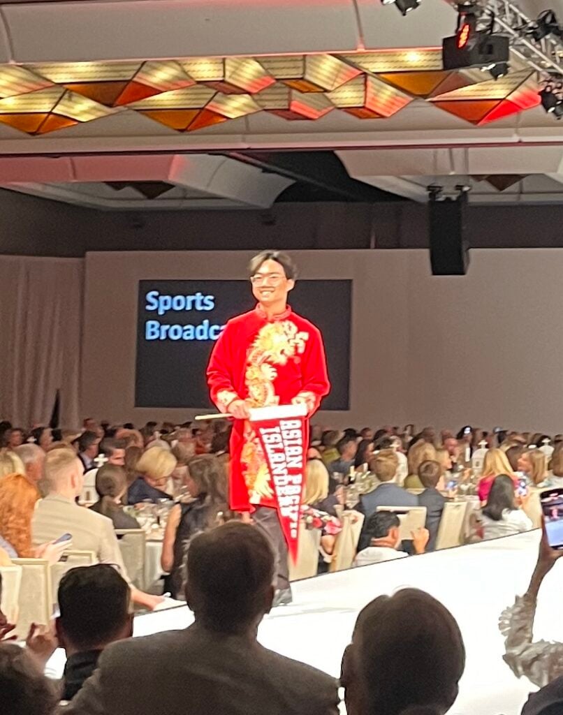 a man walking down a runway at a sports broadcast event