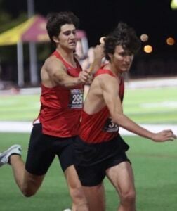 two young men are running on a track together